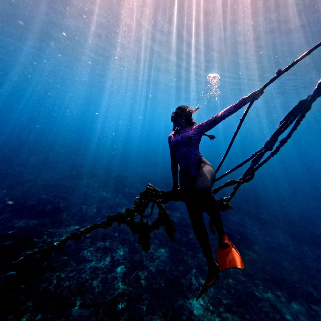 Freediver descending through beams of light